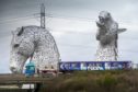 : Converted rolling stock to be used in the Scottish hydrogen trains project is driven past The Kelpies horse sculptures near Falkirk