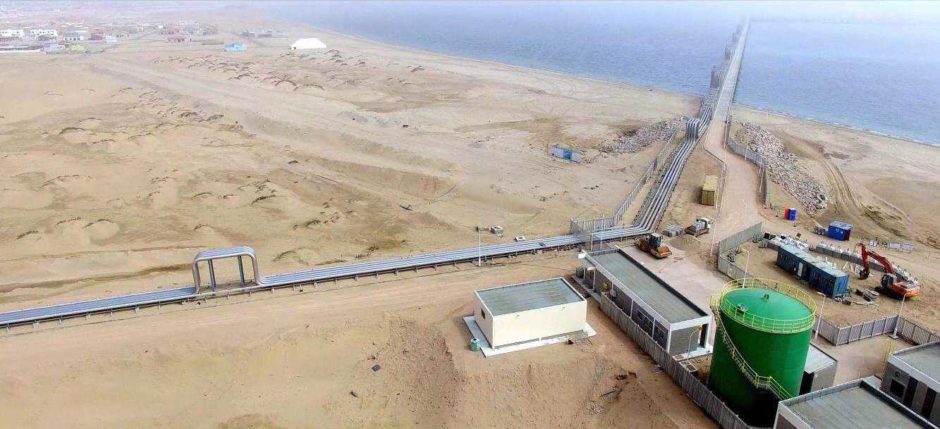 Aerial shot of industrial site, with pipeline to the left and coast in the top right