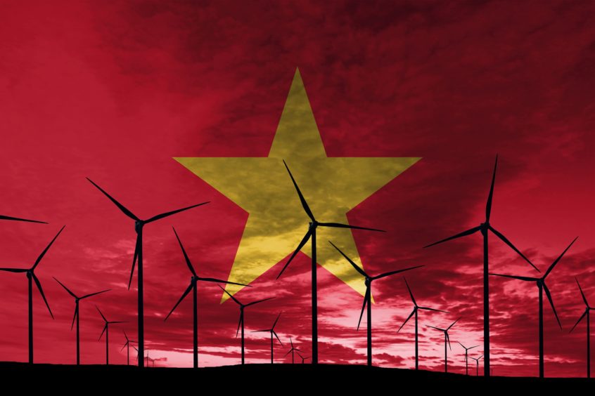 Vietnamese wind farm at sunset against the Vietnam flag.