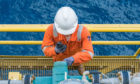 An offshore worker examining a valve
