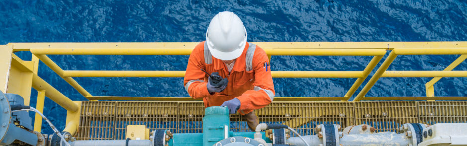 An offshore worker examining a valve