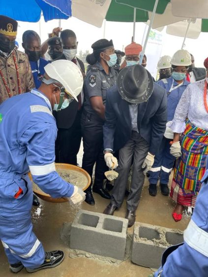 A man in a hat with a trowel puts cement on blocks