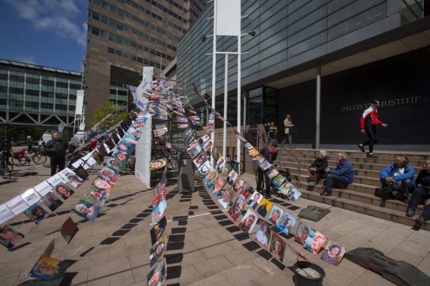 Pictures of plaintiffs fly outside the court where Milieudefensie, the Dutch arm of the Friends of the Earth environmental organization, took Shell to court, in The Hague, Netherlands, Wednesday, May 26, 2021. (AP Photo/Peter Dejong)