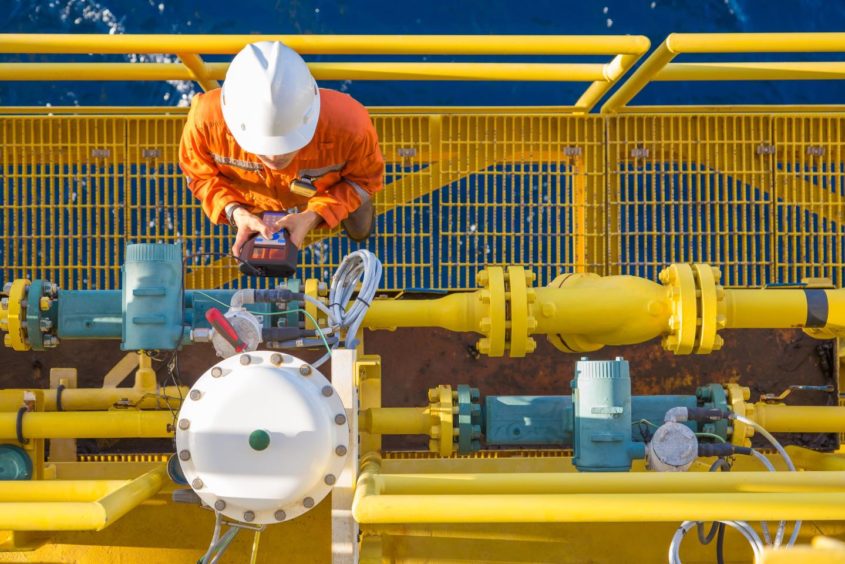 A technician checking equipment on an offshore oil and gas platform.