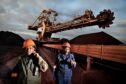 Two workers walk past coal mining equipment