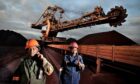 Two workers walk past coal mining equipment