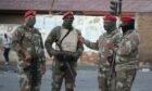 Four soldiers wearing masks in a South African settlement