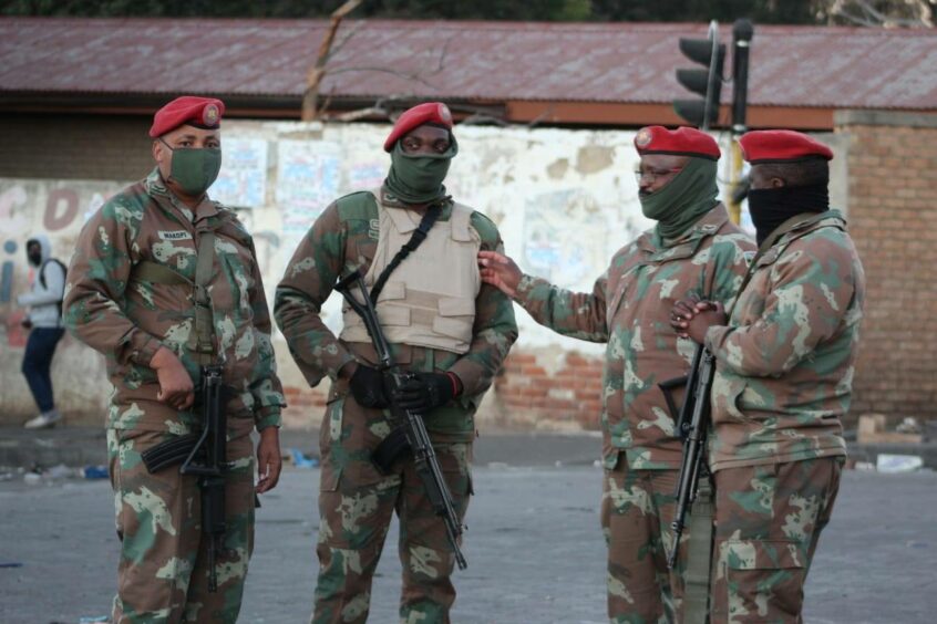 Four soldiers wearing masks in a South African settlement