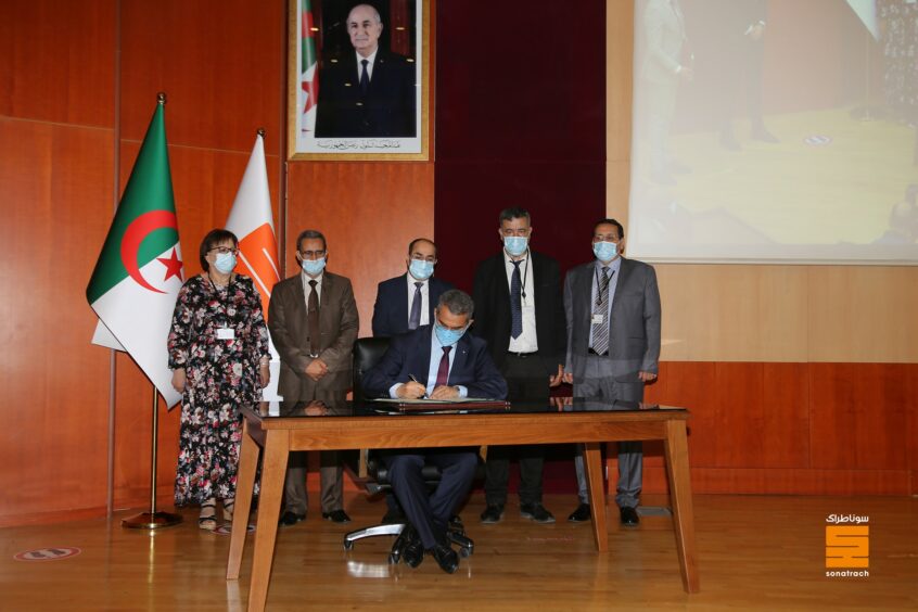 A man signs a document at a table