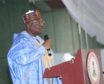 Man in Nigerian robes stands at podium