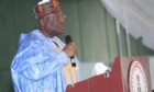 Man in Nigerian robes stands at podium