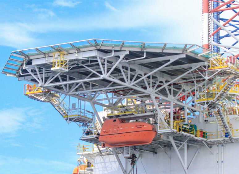 Side view of a drilling rig with lifeboat