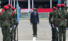 Man in suit stands between soldiers in red berets