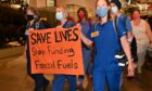 People in scrubs holding anti-fossil fuel sign