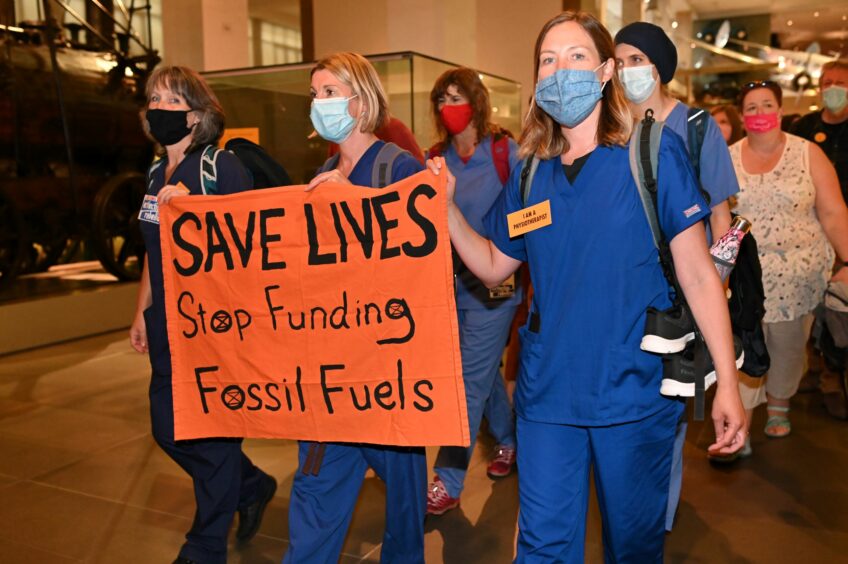 People in scrubs holding anti-fossil fuel sign