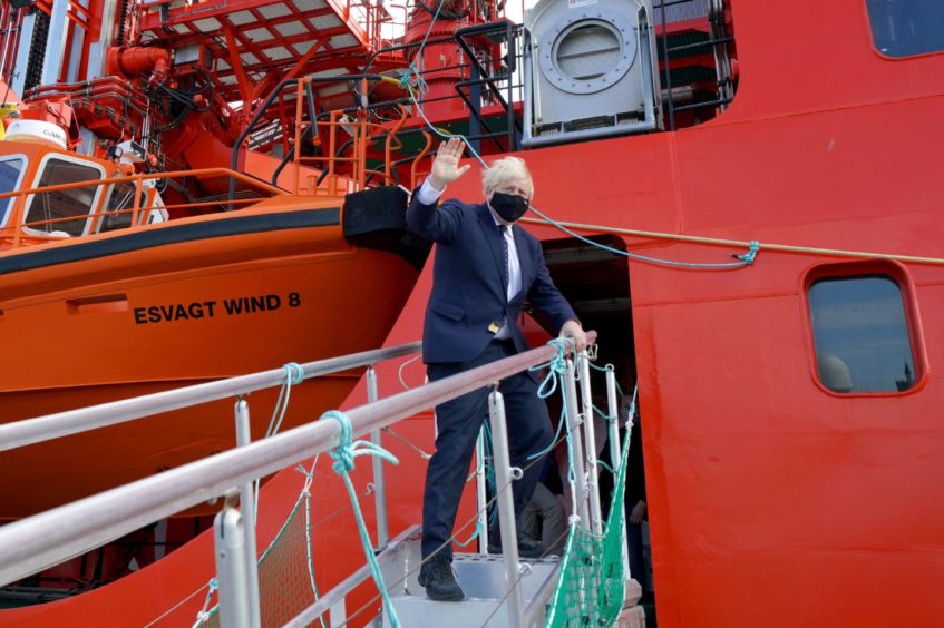 Prime Minister Boris Johnson waves as he boards the vessel Alba in Fraserburgh Harbour, Aberdeenshire, which will transport him to the Moray Offshore Windfarm East during his visit to Scotland. Picture date: Thursday August 5, 2021. Jane Barlow/PA Wire