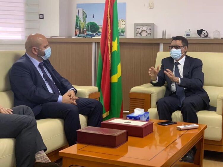 Two men sit on sofas and talk