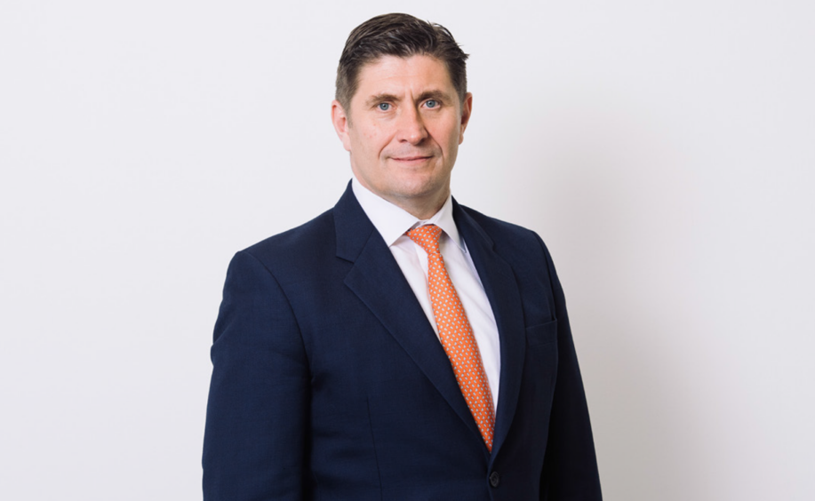 Man in suit with orange tie against pale background