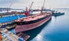 A large tanker docked next to a yellow crane