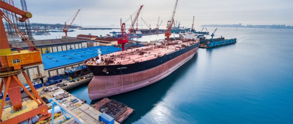 A large tanker docked next to a yellow crane