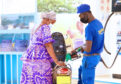 Filling up tanks at a service station, a man in a blue uniform helps