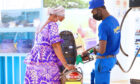 Filling up tanks at a service station, a man in a blue uniform helps