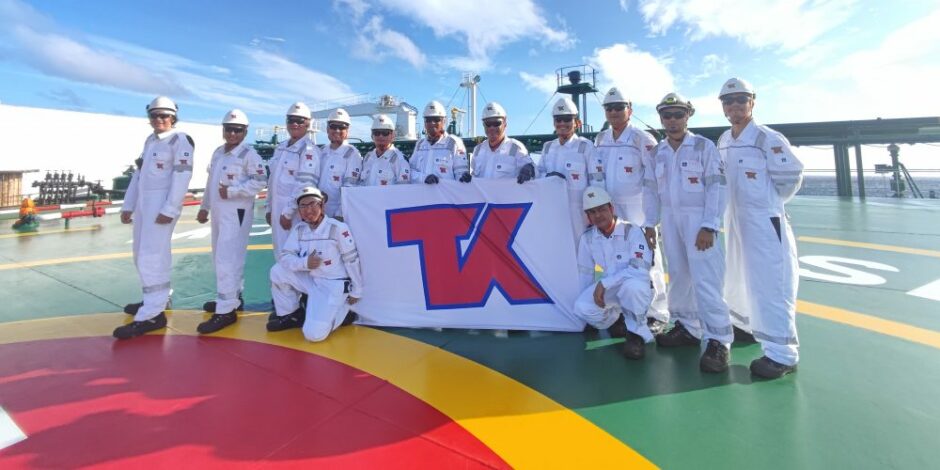 People in white suits hold a TK flag