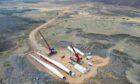 Two cranes move wind turbine blades in an aerial shot