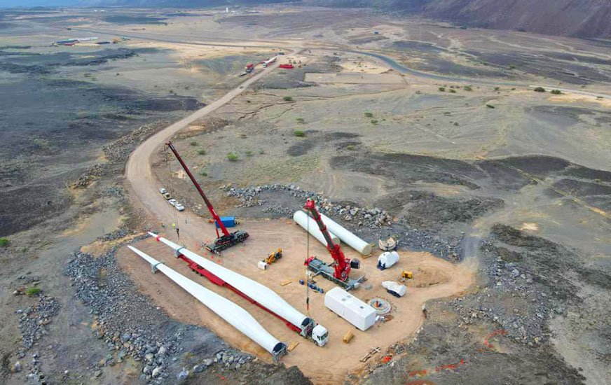 Two cranes move wind turbine blades in an aerial shot