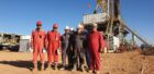 Men in overalls in front of a drilling rig