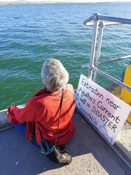 Woman sits on a dock with a protest sign