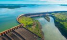 An aerial view of a dam holding back water on the lef