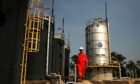 PTTEP production operator walks past crude oil storage tanks at PTTEP 1 Project site's U-Thong petroleum field, in Amphur Muang, Suphanburi province, Thailand, on Wednesday, Feb. 3, 2010.. Photographer: Dario Pignatelli/Bloomberg