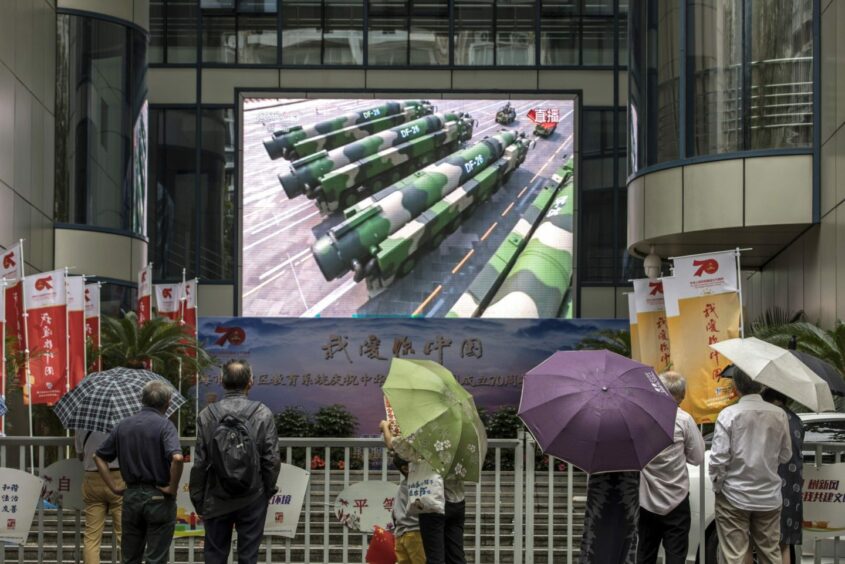 Pedestrians watch a large screen showing a live broadcast of missiles during the military parade for the 70th anniversary of the People's Republic of China in Shanghai, China, on Tuesday, Oct. 1, 2019. Photographer: Qilai Shen/Bloomberg