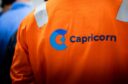 Worker wearing orange top with Capricorn written on it