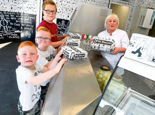 Oor Wullie’s manager Sylvia Milne serving the first customers, from left,
brothers, Lawrence, Zak
and Levi Jaffrey