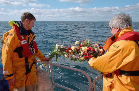 A member of the Fraserburgh Lifeboat crew, left, helps the Reverend Andrew Jolly lay wreaths