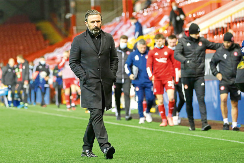 Derek McInnes walks across the Pittodrie pitch.