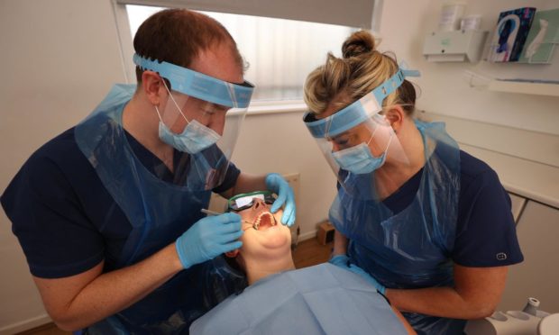 Dentists in PPE during an examination.