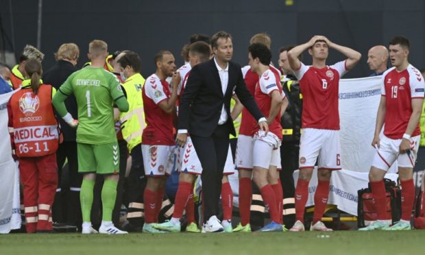 Denmark's managaer Kasper Hjulmand, centre, and players gather around Christian Eriksen as he receives medical attention