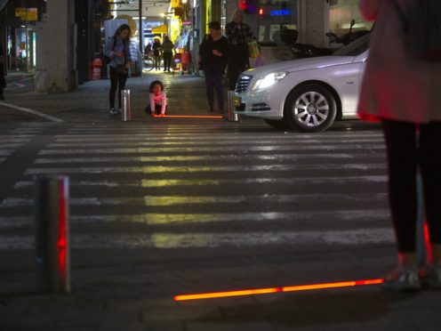 An Israeli child plays with an embedded LED light at a crossing in Tel Aviv (Sebastian Scheiner/AP)