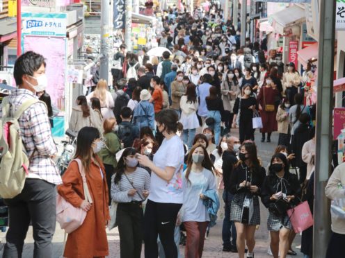 People wearing face masks to protect against the spread of the coronavirus walk on a street in Tokyo (AP)