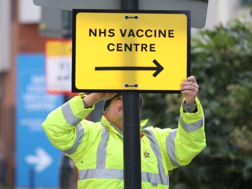 A Brent council worker hangs a direction sign to the Covid-19 vaccine centre at the Olympic Office Centre in Wembley (Yui Mok/PA)
