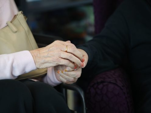 A care home resident holds hands with a visitor (Aaron Chown/PA)