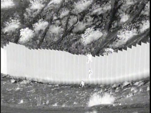 This photo taken from night video provided by US Customs and Border Protection shows a smuggler dropping children from the top of border barrier in Santa Teresa, New Mexico (US Customs and Border Protection/AP)