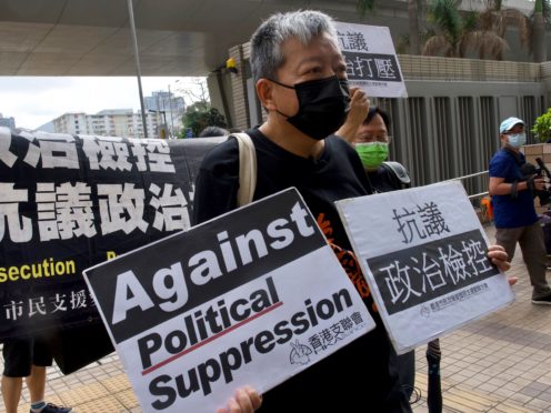 Pro-democracy activist Lee Cheuk-yan holds placards as he arrives at a court in Hong Kong where he was one of seven people convicted on charges of organising and participating in an unlawful assembly (Vincent Yu/AP)