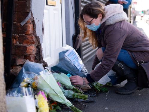 A woman lays flowers at the scene on High Street, Brownhills, near Walsall in the West Midlands, where a two-week-old baby boy in a pram was hit by a BMW car at around 4pm on Easter Sunday. West Midlands Police said the baby was rushed to hospital but nothing could be done to save him. Picture date: Monday April 5, 2021.