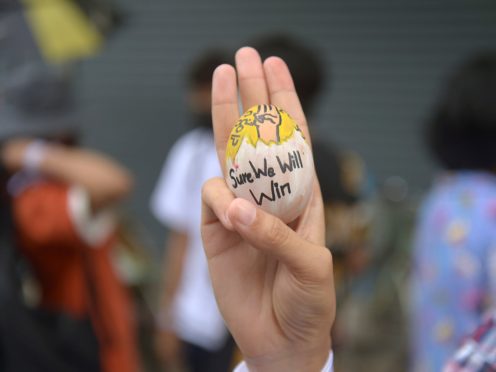 An anti-coup protester raises a decorated Easter egg along with the three-fingered symbol of resistance during a protest against the military coup (AP)
