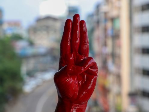 An anti-coup protester shows the three fingered salute of resistance on his red painted hand in memory of protesters who lost their lives (AP)