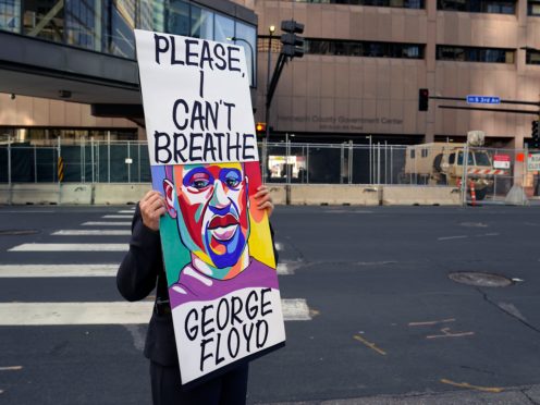 A protester holds a sign across the street from National Guard soldiers guarding the Hennepin County Government Centre, the trial venue (Jim Mone/AP)
